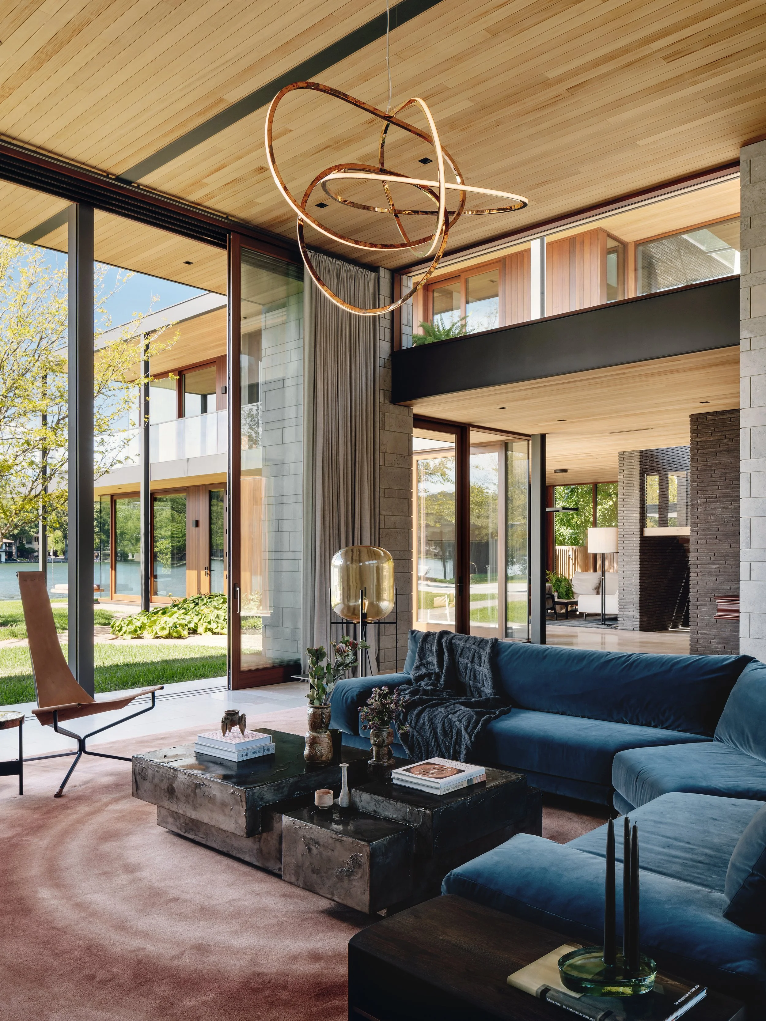 Water's Edge living room with Christophe Delcourt sectional, custom rug, and Niamh Barry bronze chandelier, designed by Cravotta Interiors